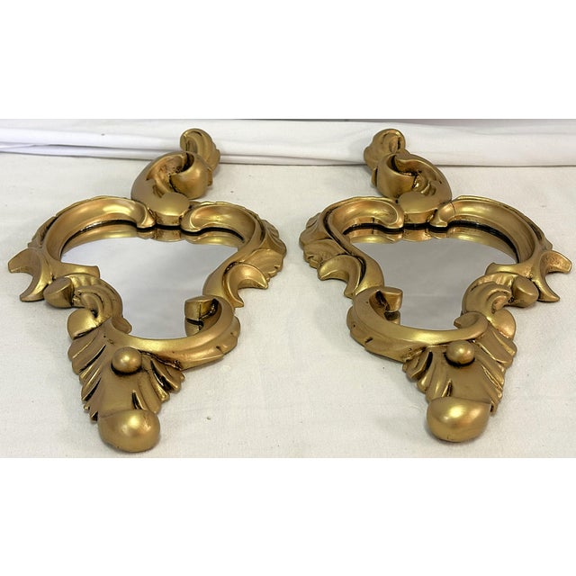 Sweet petite pair of scroll wall mirrors. They have an Art Nouveau/ Rococo cornucopia style with an antique gold painted...