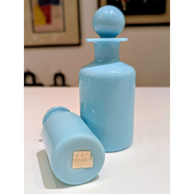 A graduated pair of opaque blue glass decanters produced by P.V. France in the 1960s. Clean cylindrical forms are topped...