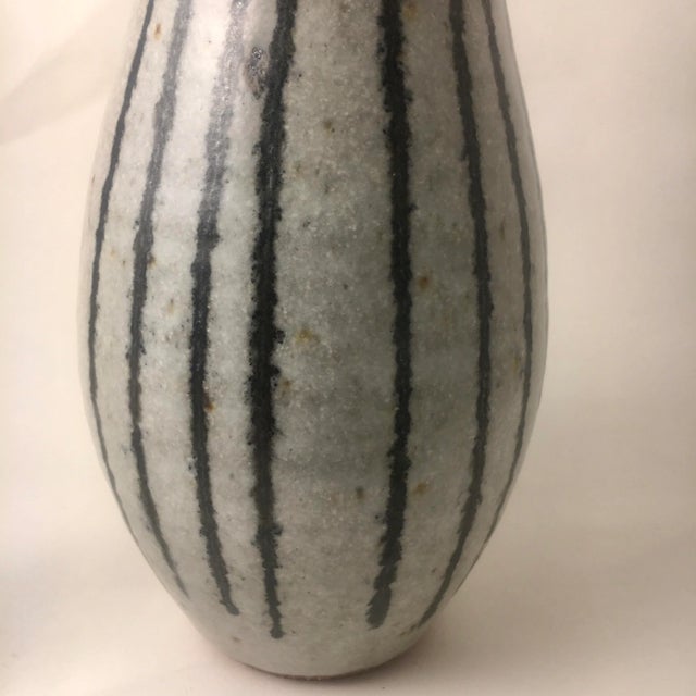 This Mid-Century 9" bottle-shaped vase has a graphic striped body and a unique mottled grey glaze. Made circa the 1960s in...