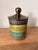 A stunning piece from celebrated Ecuadorian artist, Eduardo Vega. This banded beauty features a metallic bronze glazed lid...