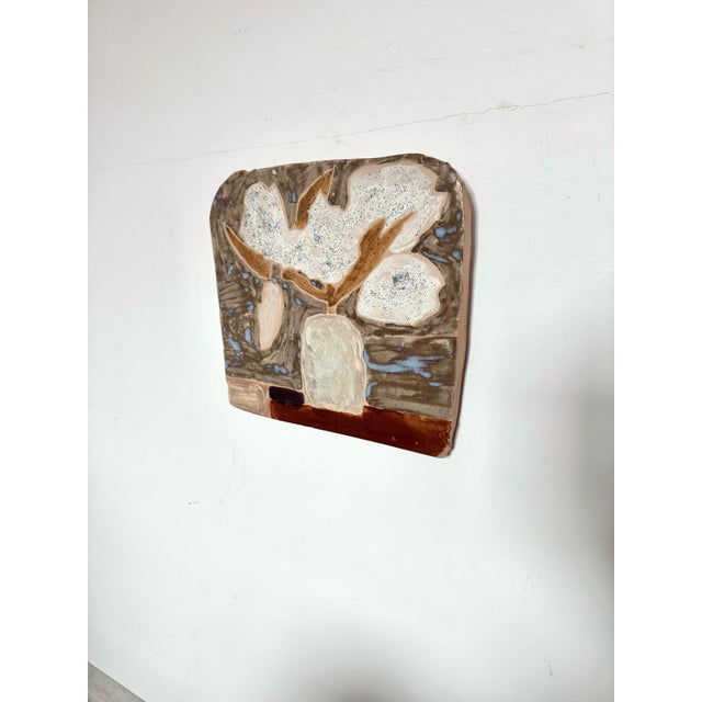 This is a hand-built ceramic wall plaque featuring an abstract still life of flowers in a vase. This piece is handmade,...