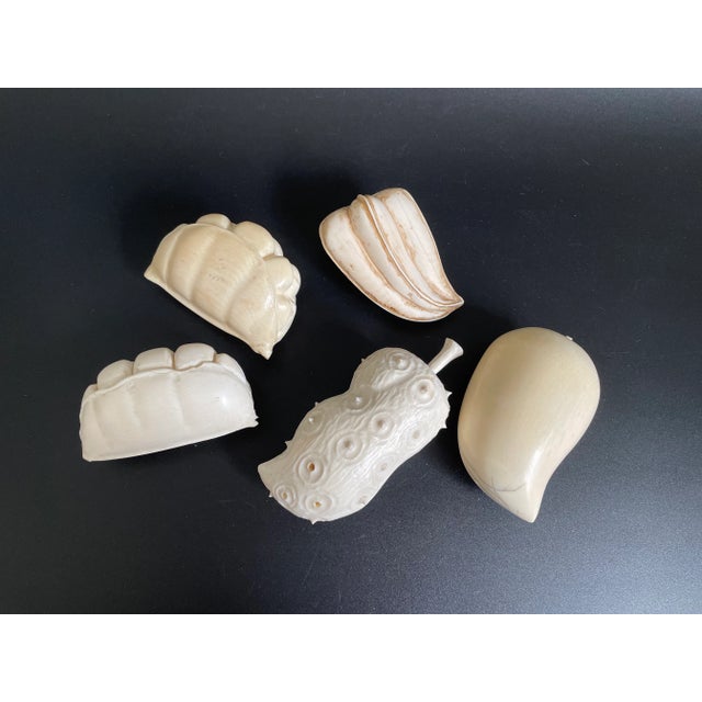 Presenting a rare collection of five African carved fruits or vegetables, including kiwano, mango, tamarind (or peas), and...