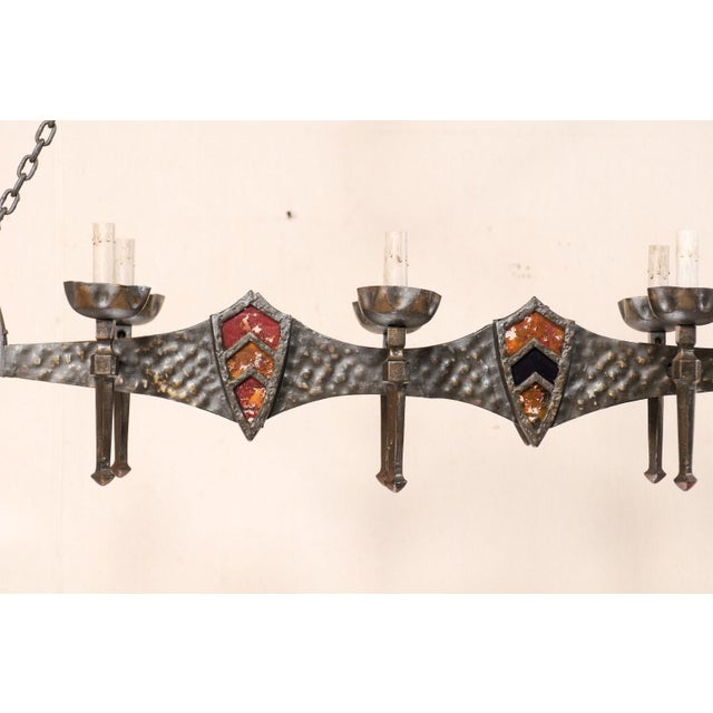 A vintage French six-light chandelier. This French chandelier from the mid 20th century of forged iron has a slender...