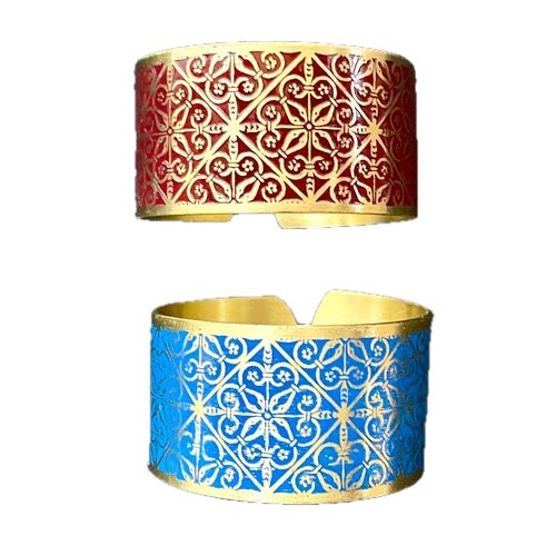 Pair of vintage brass and enamel napkin rings. Abstract flour de lis and floral geometric pattern. No maker's marks.