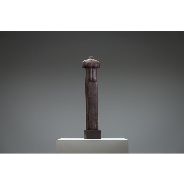Carved from a single block of aged wood, the torso stands with a quiet authority—its surface worn smooth in some places,...