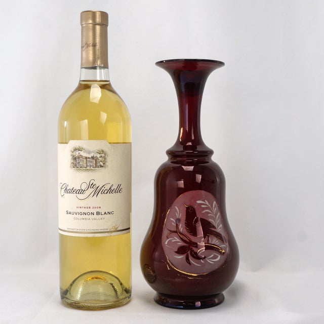 A colorful hand-blown Bohemian ruby glass art vase decorated of a bird in a tree. The thin glass vase with a flared mouth...