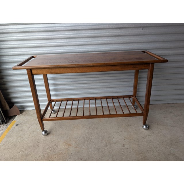 Wonderful rolling cart in what appears to be walnut, with integrated handles, delicate bottom spindle shelf, tapered legs...