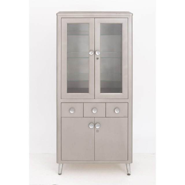 Art Deco Style Gray Patinated Metal Display Cabinet, with two glass-paneled doors with three glass shelves above three...