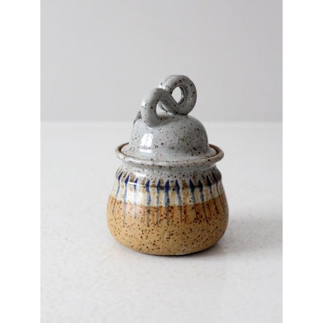This vintage studio pottery jar features a sculptural handle on its fitted lid and a subtly textured, handmade form. Its...
