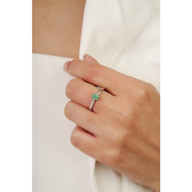 Featuring a 3×5 mm octagon-cut emerald gemstone (0.28 carat), this ring is enhanced with delicate diamond accents (0.04...