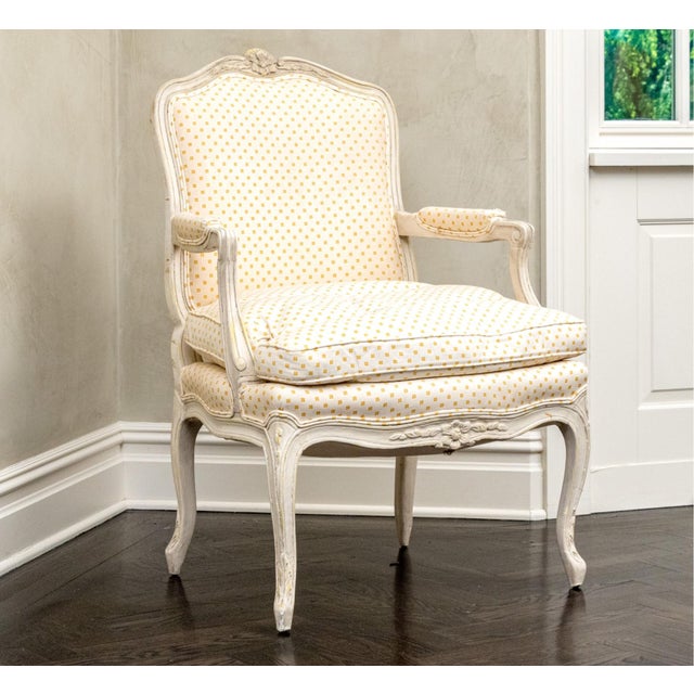 A pair of early 20th century Louis XV style painted bergère armchairs featuring carved hardwood frames, cabriole legs,...