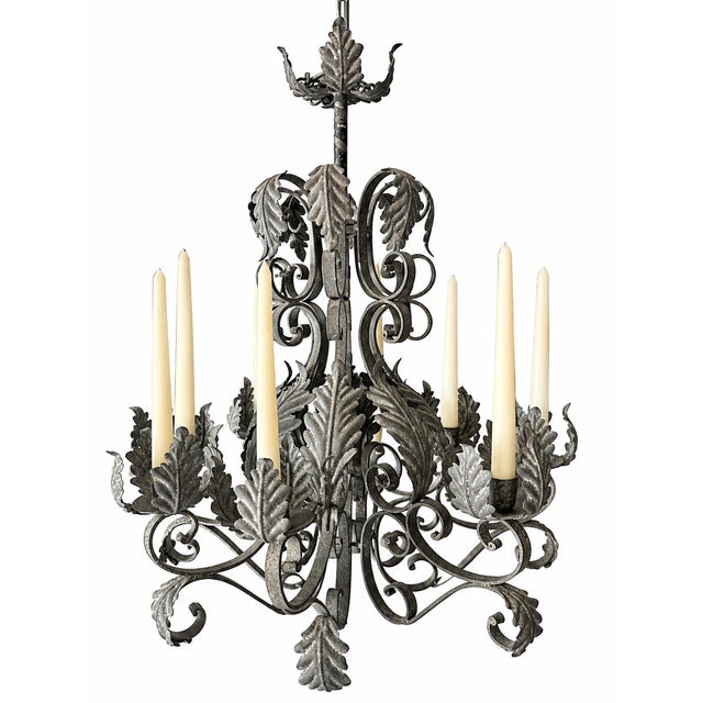 Large and heavy French-style wrought iron and tole chandelier featuring elaborate scrolling metalwork and dimensional...
