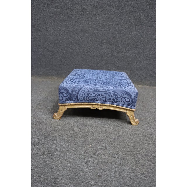 Louis XV style ottoman featuring a carved and painted wood frame with graceful scroll feet and decorative apron detailing....