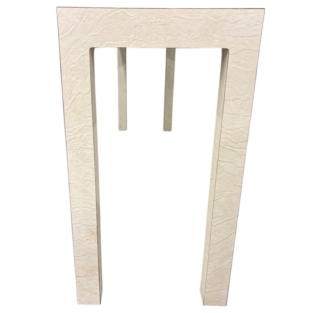 Unmarked off-white console table with a wood frame and a white, textured surface applied over top the wood as a decorative...