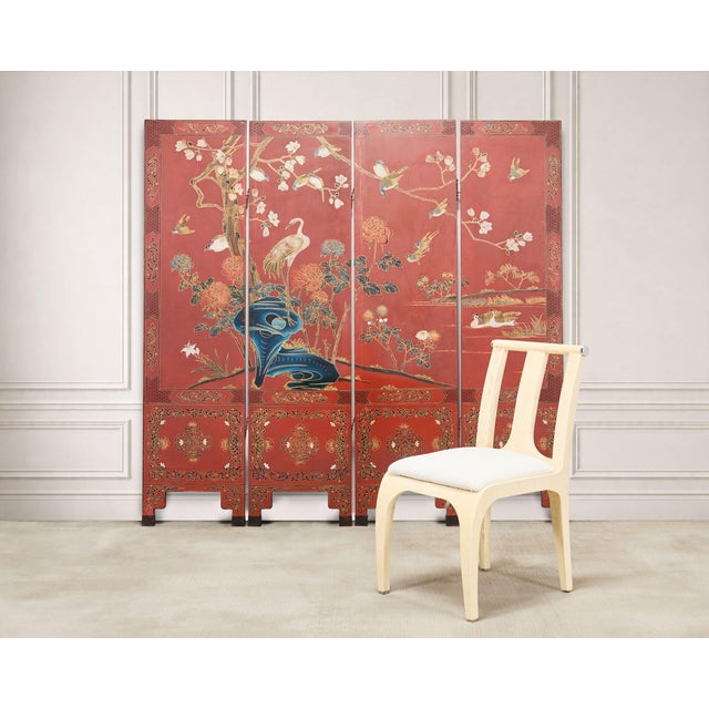 A highly decorative four-panel red lacquer folding Chinese Export Coromandel screen, richly decorated with a continuous...