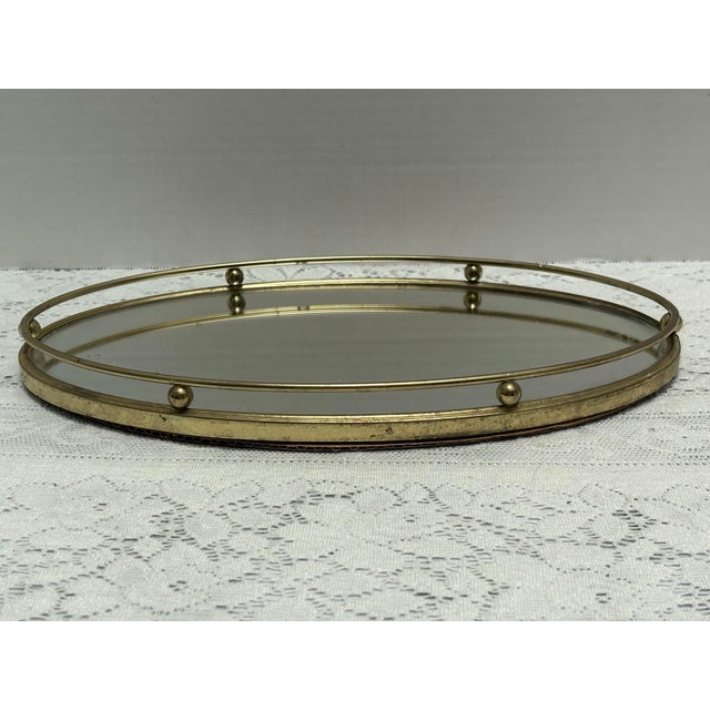 Vintage oval gold toned mirror tray with raised border and ball accents, and felt covered bottom. 1960s to 1970s era....