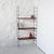 Modular hanging shelving unit with black lacquered metal side panels and teak veneer shelves with brass hooks. Designed...