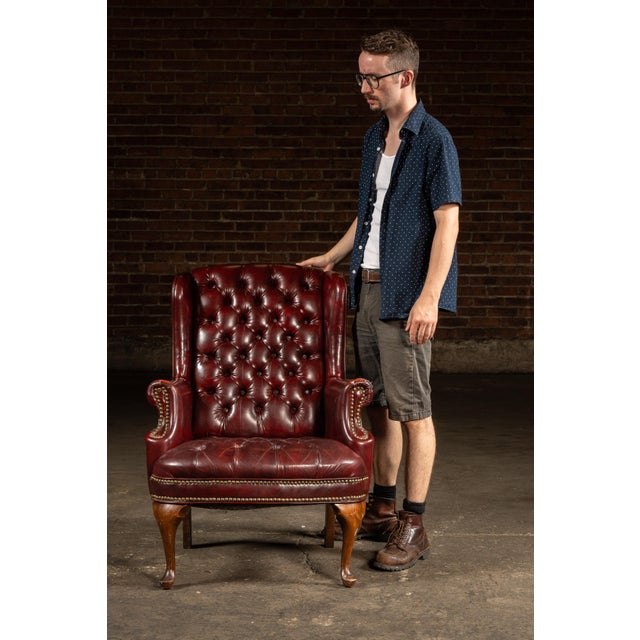 Handsome tufted leather armchair upholstered in deep oxblood leather, with button-tufting across the high back and seat....