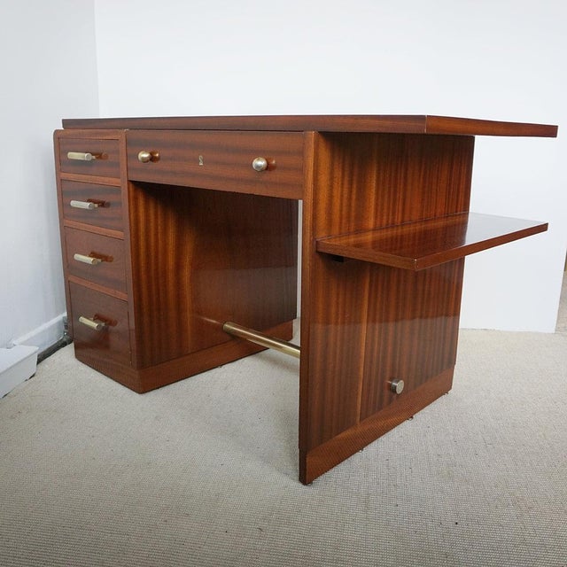 An Art Deco Figured Walnut Desk. Five pull out drawers with an open bookshelf to side. Original brass handles and...
