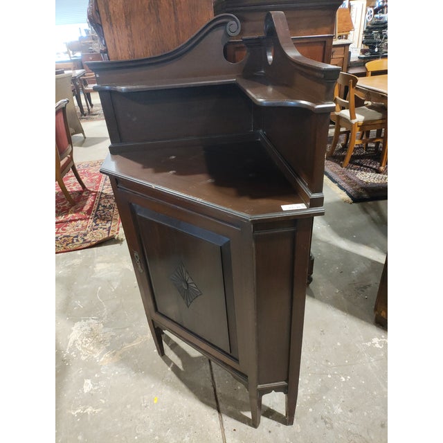 Elegant Federal-style corner cabinet featuring a shaped swan-neck gallery back with open circular cutouts and a central...
