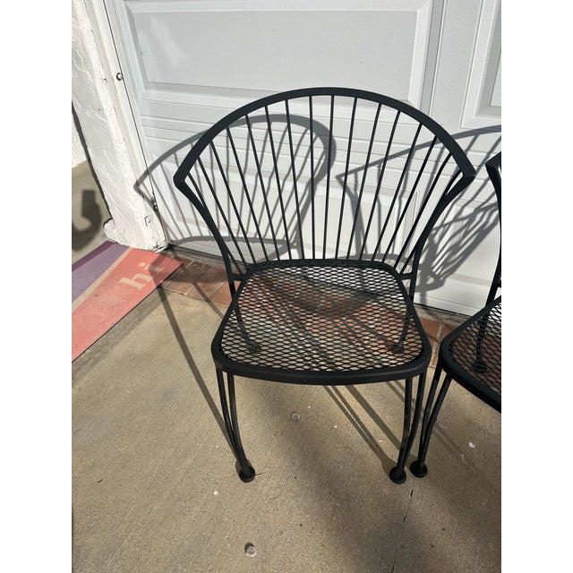 A vintage 1950s wrought iron pair of garden dining chairs in style of Woodard. These are unmarked and repainted, but could...