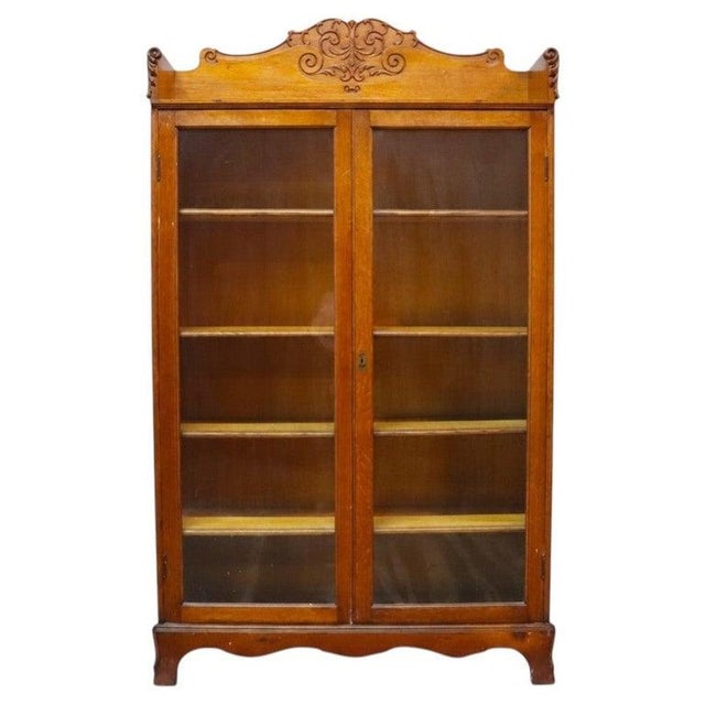 An antique two-door bookcase attributed to R.J. Horner, crafted from carved oak and dating to approximately 1920. This...