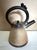 A sculptural studio teapot by American potter Mark Untener, c. 1990s–2000s. The conical tan stoneware body is carved with...