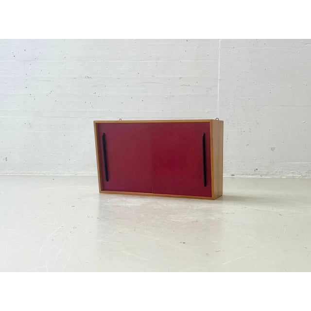 A characterful mid-century wall cabinet from the 1950s to 1960s with a clear, functional design. The warm-toned wooden...
