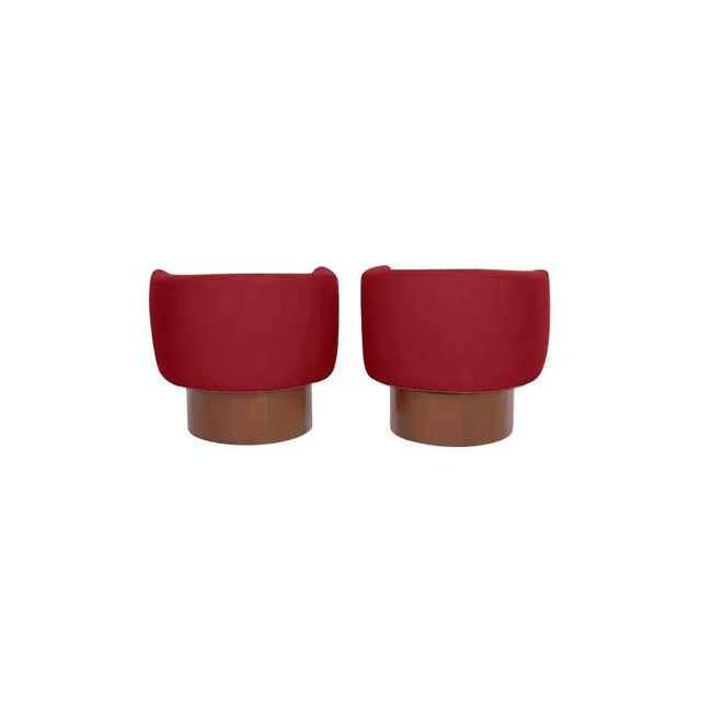 Pair of modern club chairs with walnut base. The chairs swivel. The chairs are done in a red chenille. The chairs are...