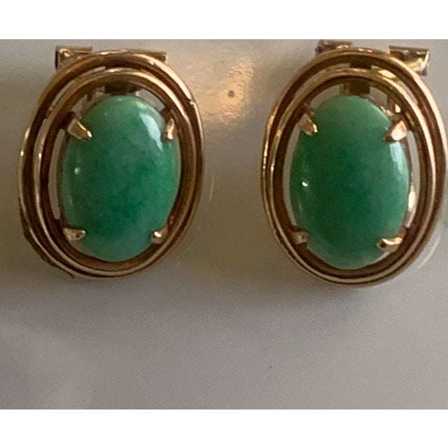 Beautiful vintage earrings crafted in 14K yellow gold and set with polished oval jade cabochons. The jade stones display a...