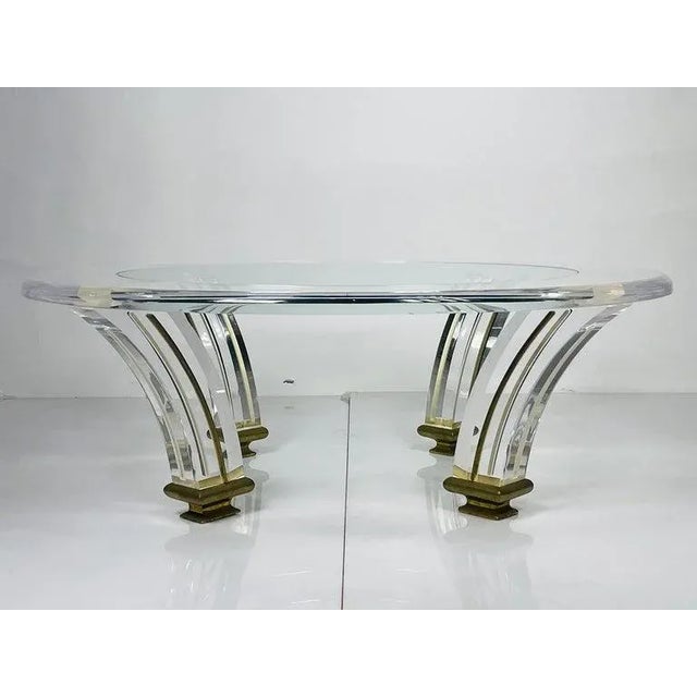 Vintage coffee table executed in Lucite, brass and glass. The base has a splayed tusk shaped legs with brass detail runing...