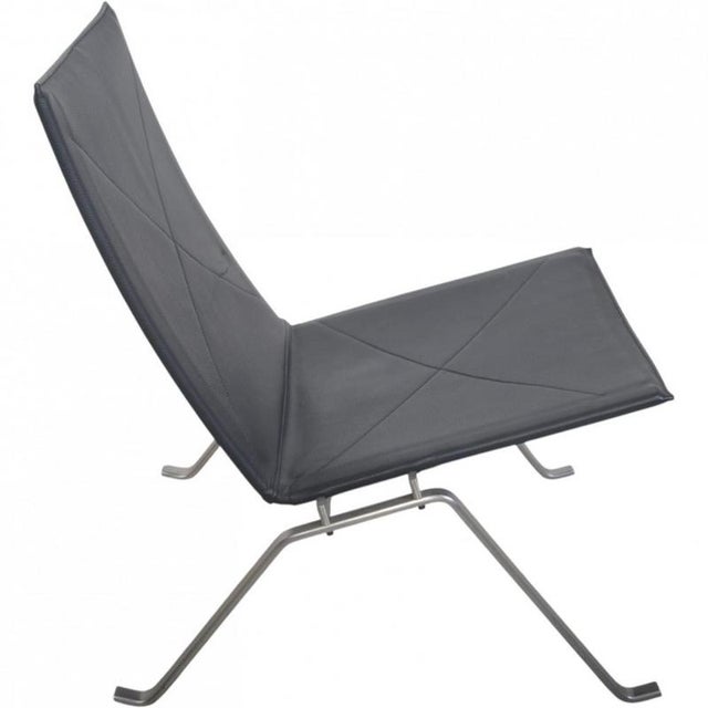Poul Kjærholm PK22 chair upholstered in black aura leather, and with a frame of brushed spring steel. The chair is from...