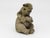 An English late-20th-century composite stone garden statue depicting a seated elephant with rounded, stylized features and...