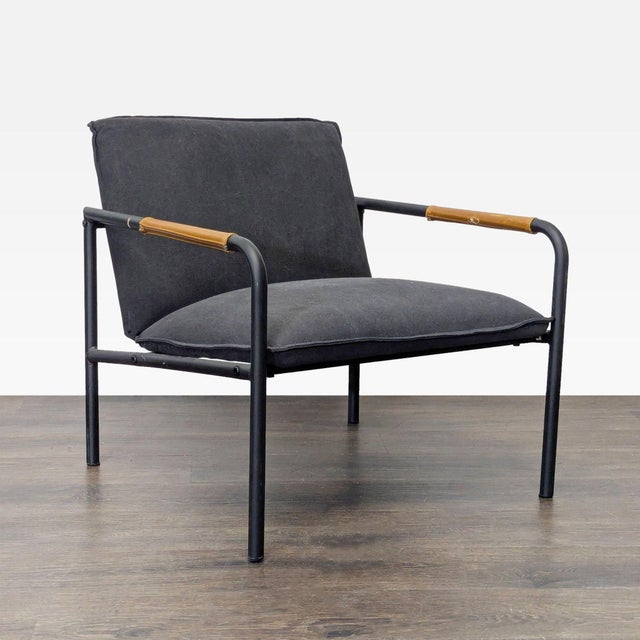 This Sauder lounge chair features a sleek black cushion with a sturdy black metal frame and wooden accents on the...