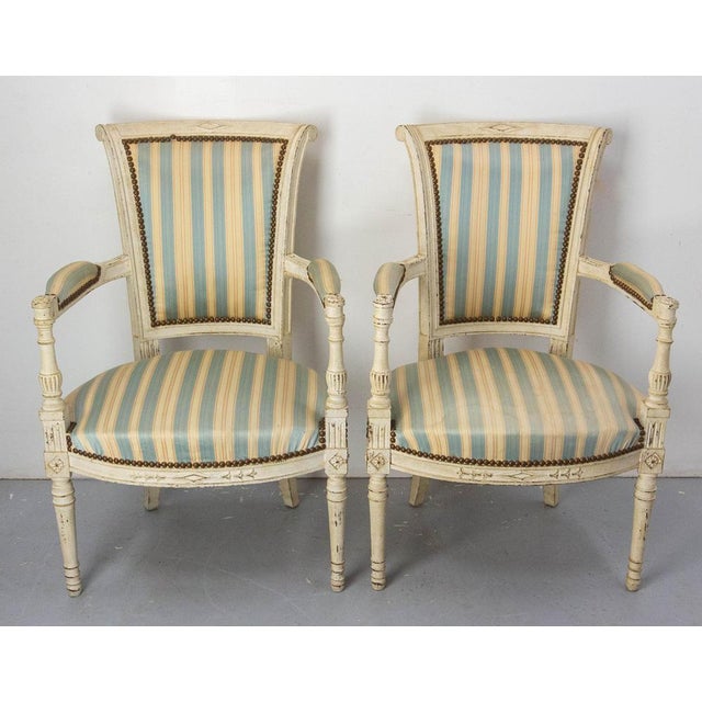Pair of Louis XVI style fauteuils, French open armchairs, made in the 20th mid-century period. The wood is finely scupted...