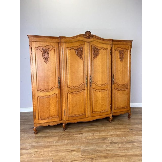 An impressive Vintage French Louis wardrobe in oak, featuring four beautifully shaped panelled doors enriched with...