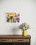 A lively arrangement of vintage pitchers, vases, and glassware unfolds across a patterned tabletop, each form distinct yet...