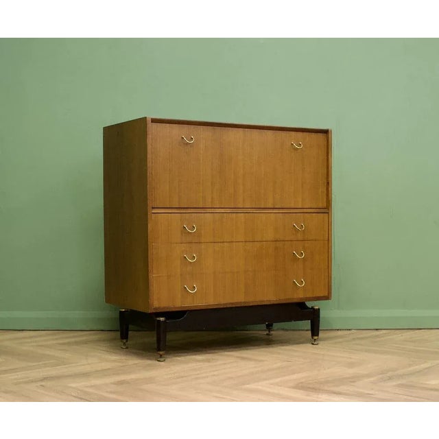 A mid century tola and black tallboy chest from g plan (e gomme) featuring a pull down compartment with an internal shelf...