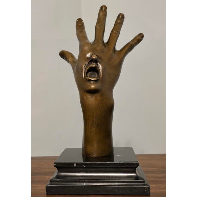 A dramatic solid bronze surrealist hand sculpture, signed by the artist and mounted on a polished black marble base. This...