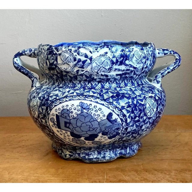 This vintage blue and white jardiniere is a richly patterned piece of chinoiserie porcelain, with a broad, bulbous body...