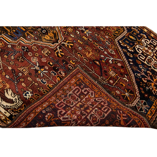 Beautiful Antique Persian Shiraz Handmade Wool rug with an all-over rust field. This piece has multi-color accents in a...