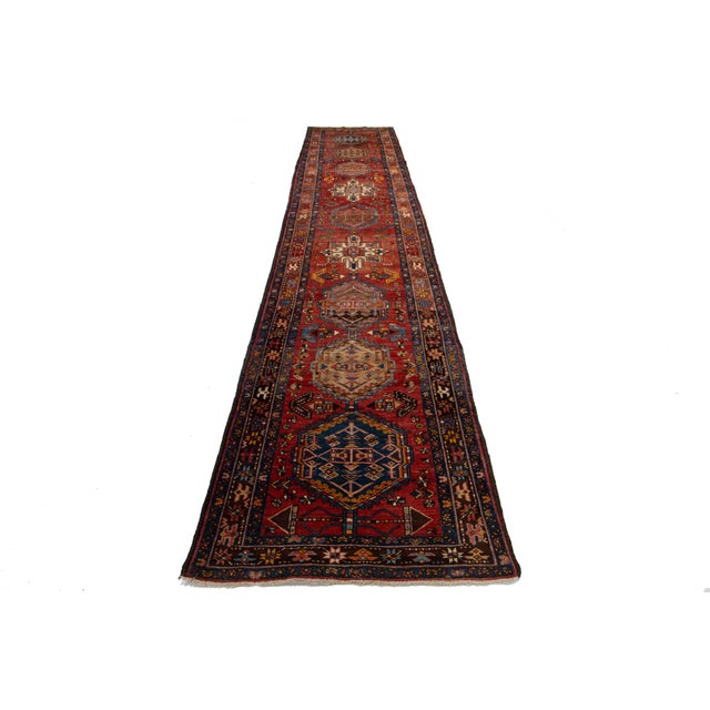 This beautiful 20th-century Persian Heriz Handmade wool rug has a red field with multicolor accents throughout the design....