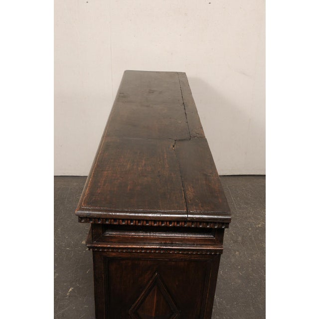 A stately Italian carved walnut sideboard, with diamond panel accents, from the early 18th century. This antique buffet...