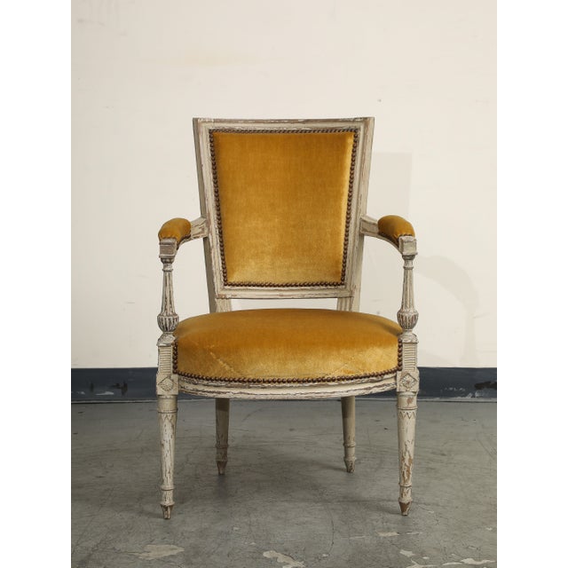 19th Century French Directoire carved walnut armchair with white paint and gold velvet upholstery.