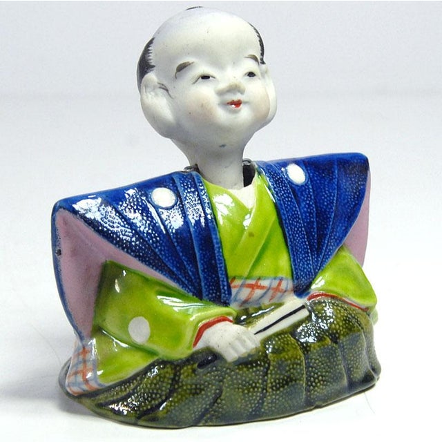 Decorative, oriental porcelain figurine made of white bisque porcelain. The head is placed on a pole and a counterweight...