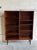 This beautiful open-face shelving unit displays a minimalist tall silhouette raised on round tapered legs. The...