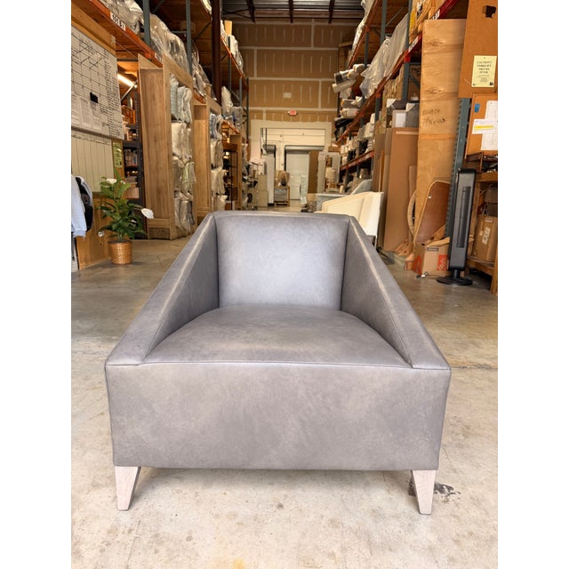 Contemporary leather accent chair featuring a bold architectural silhouette with clean lines and angled track arms for a...