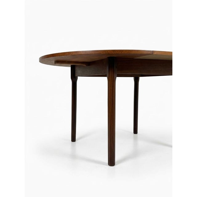 Extendable round teak table made in Italy in the 1960s. The table comes with four chairs upholstered in black faux...