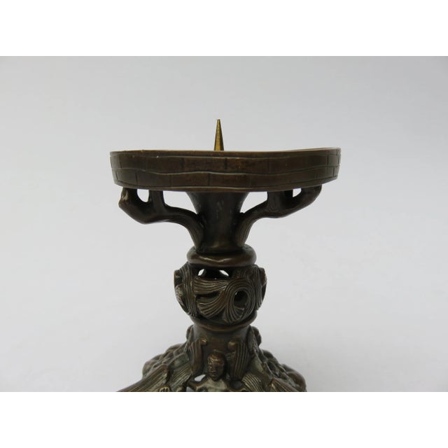 Pair of cast bronze candlesticks manufactured in the 19th century. They are set on three feet each with a central figure...