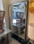 A 1970s entryway mirror unit with a built-in coat rack. The mirror is framed by a mosaic of mirror tiles and screen-...